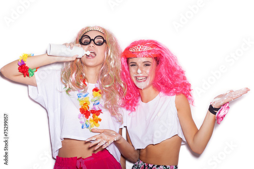 Funny girls in colored wigs and glasses stained with cream
