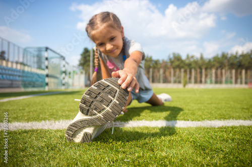 young girl stretching on grass before running