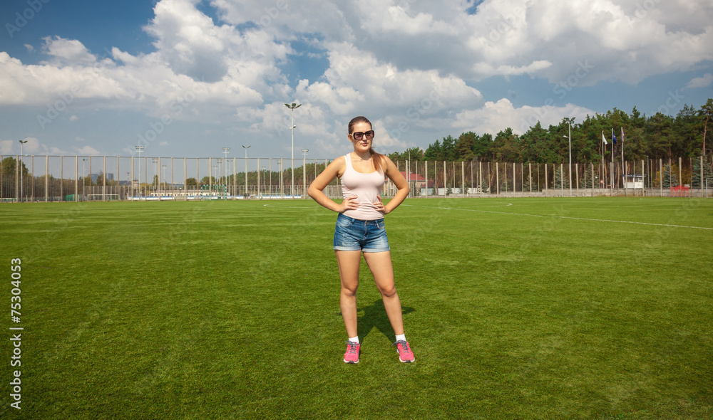 slim woman standing on soccer field at sunny day