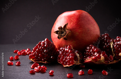 Some red pomegranates on black slate plate