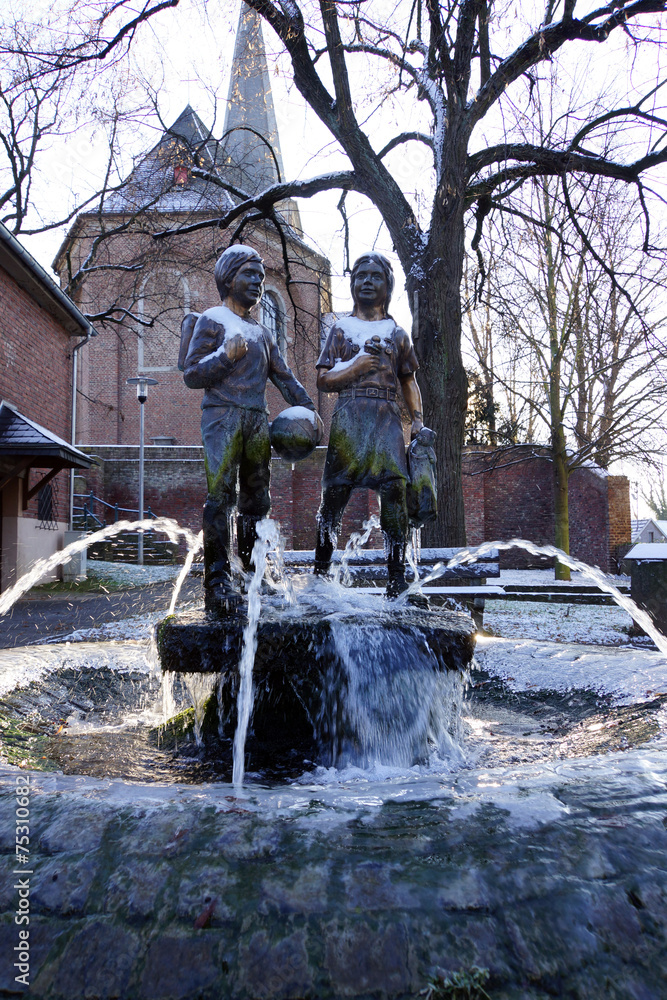 Brunnen mit zwei Schulkindern im Winter