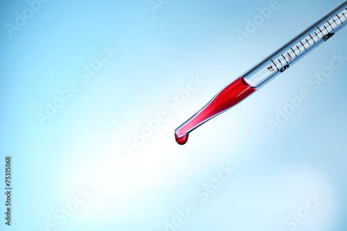 Pipette adding red fluid to the one of test-tubes