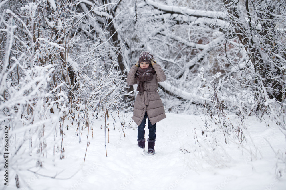 Happy little girl on the background of a winter park