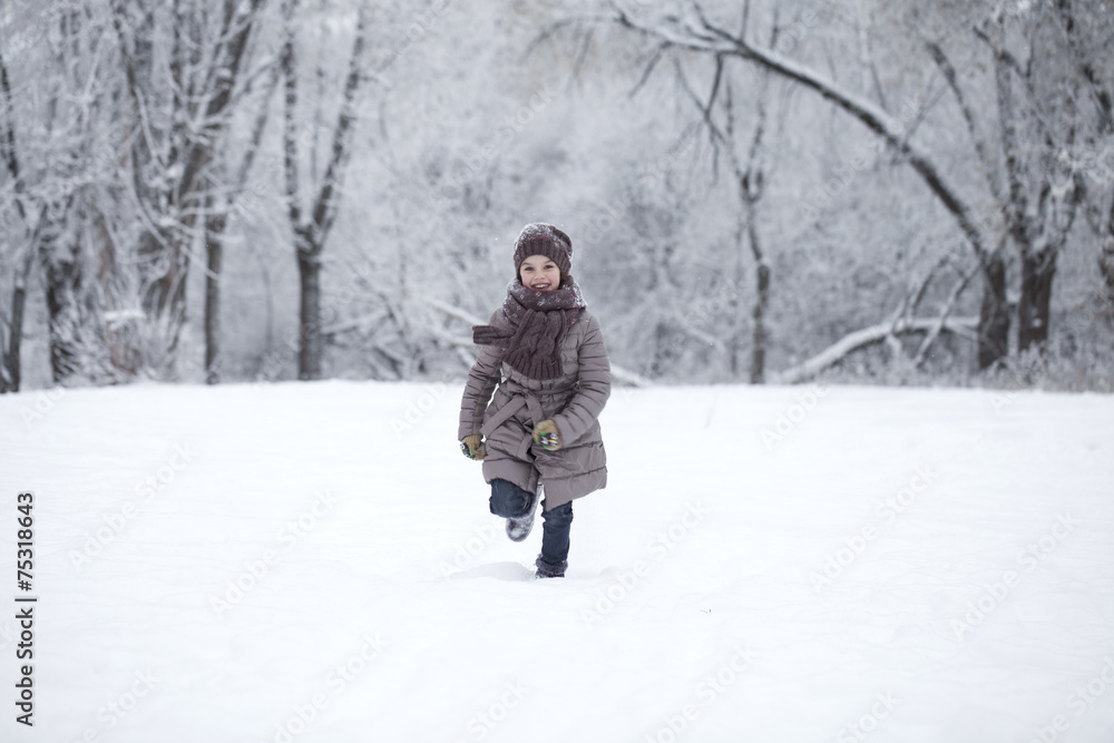 Happy little girl running on the background of snow covered wint Happy little girl running on the background of snow covered wint