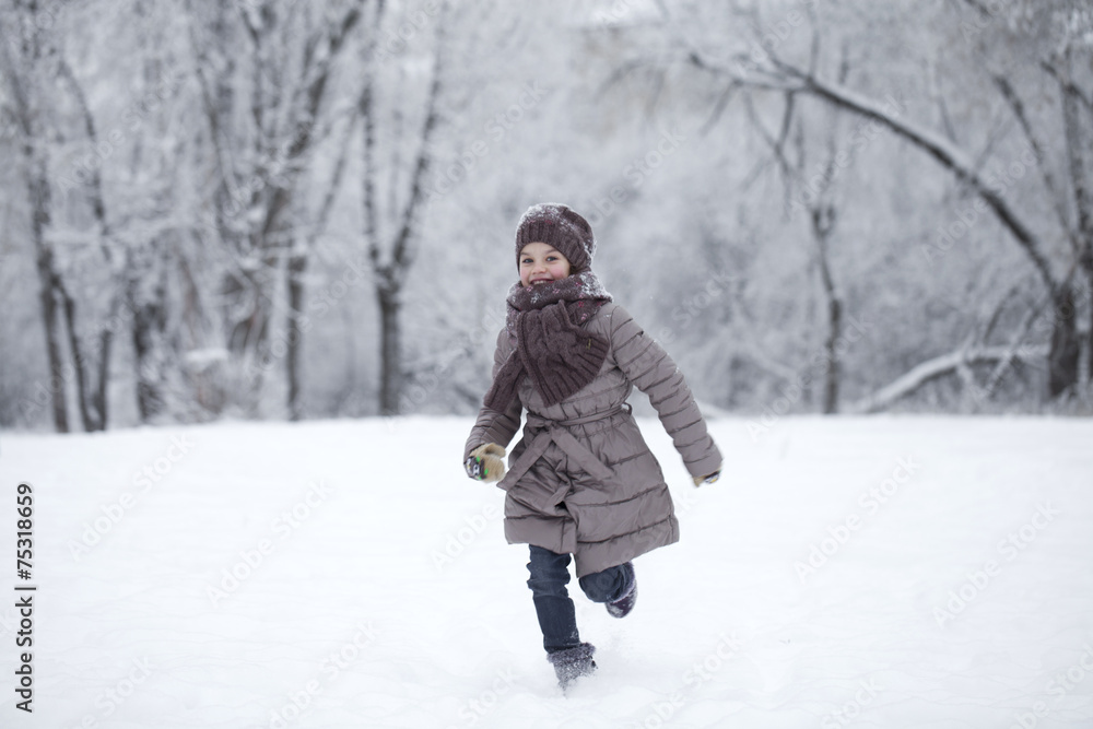 Happy little girl running on the background of snow covered wint Happy little girl running on the background of snow covered wint
