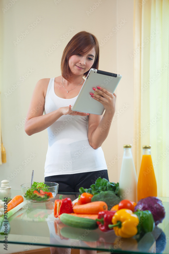 Young woman Following Recipe On Digital Tablet