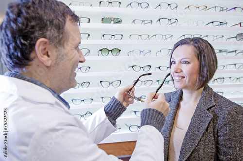 optician trying on glasses to a customer photo