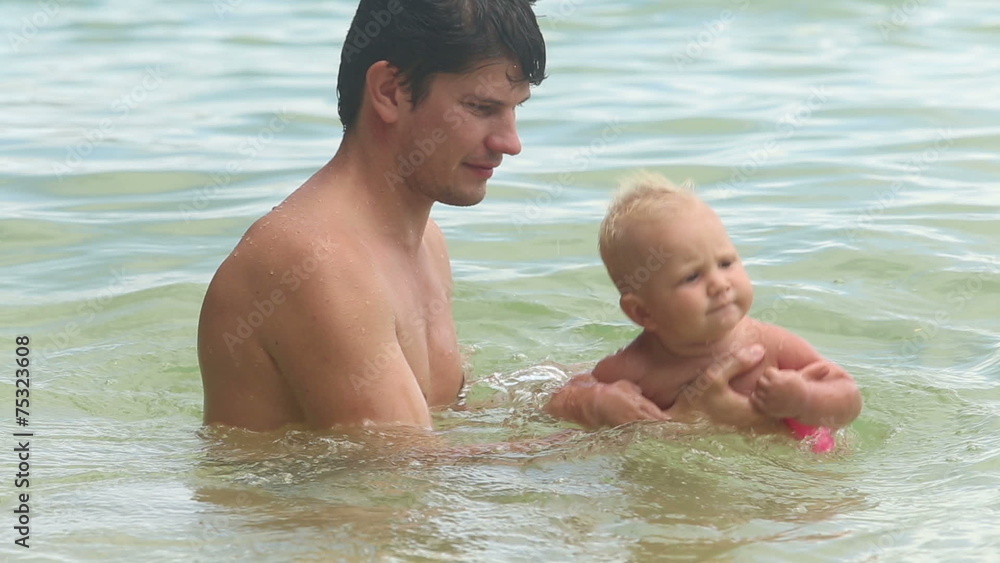 European dad bathe his baby daughter in the blue sea European dad bathe his baby daughter in the blue sea