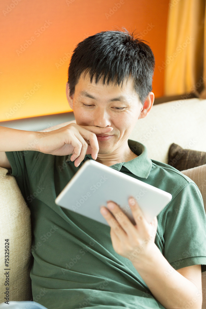 Asian young adult man using tablet and relax on sofa. Asian young adult man using tablet and relax on sofa.