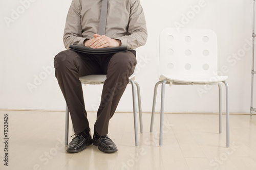 Geschäftsmann auf dem Stuhl und wartet, niedrige Abschnitt © tunedin