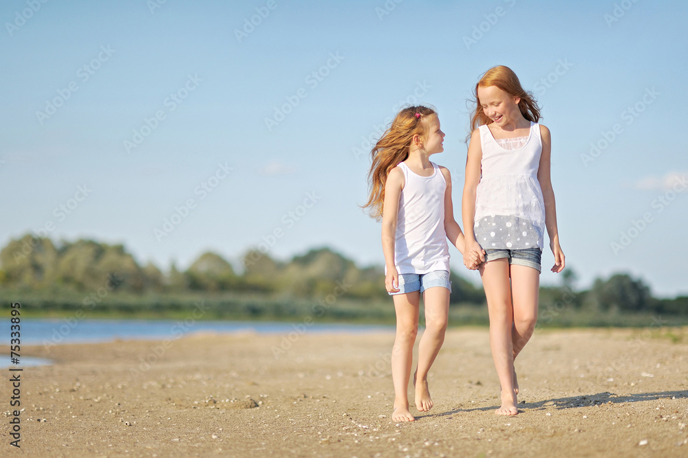 portrait of two sisters walking on the beach