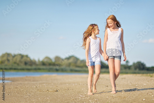 portrait of two sisters walking on the beach