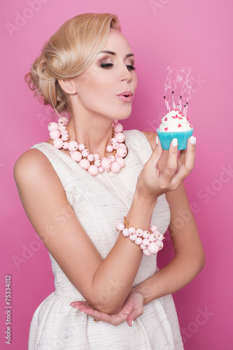Elegant woman blowing out candles on birthday cake