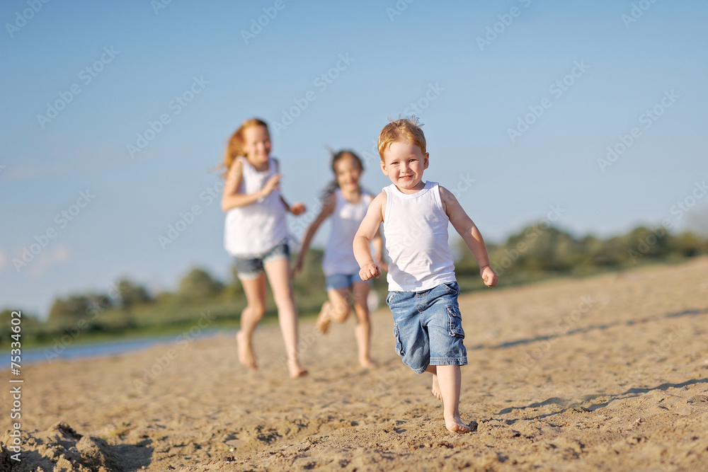 three children playing on beach in summer three children playing on beach in summer