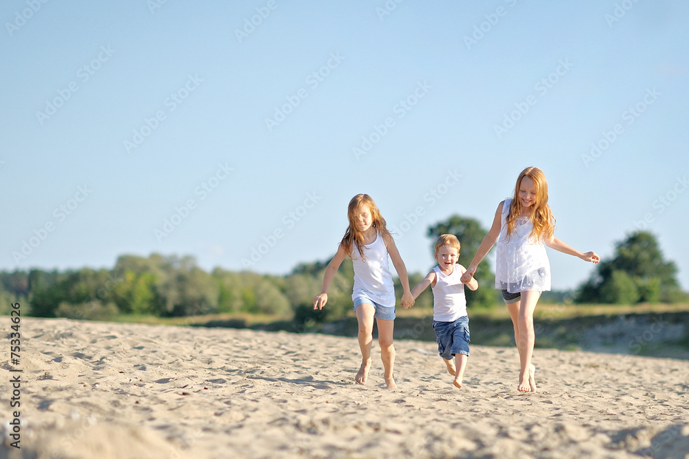 three children playing on beach in summer three children playing on beach in summer