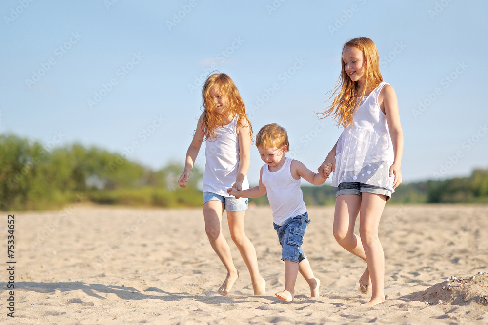 three children playing on beach in summer
