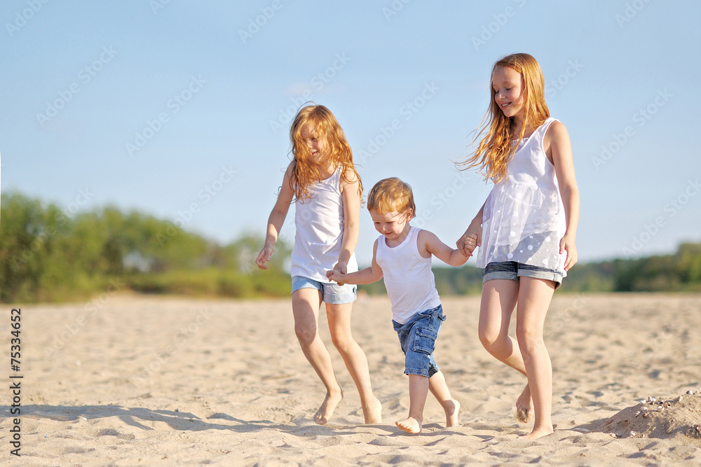 three children playing on beach in summer three children playing on beach in summer