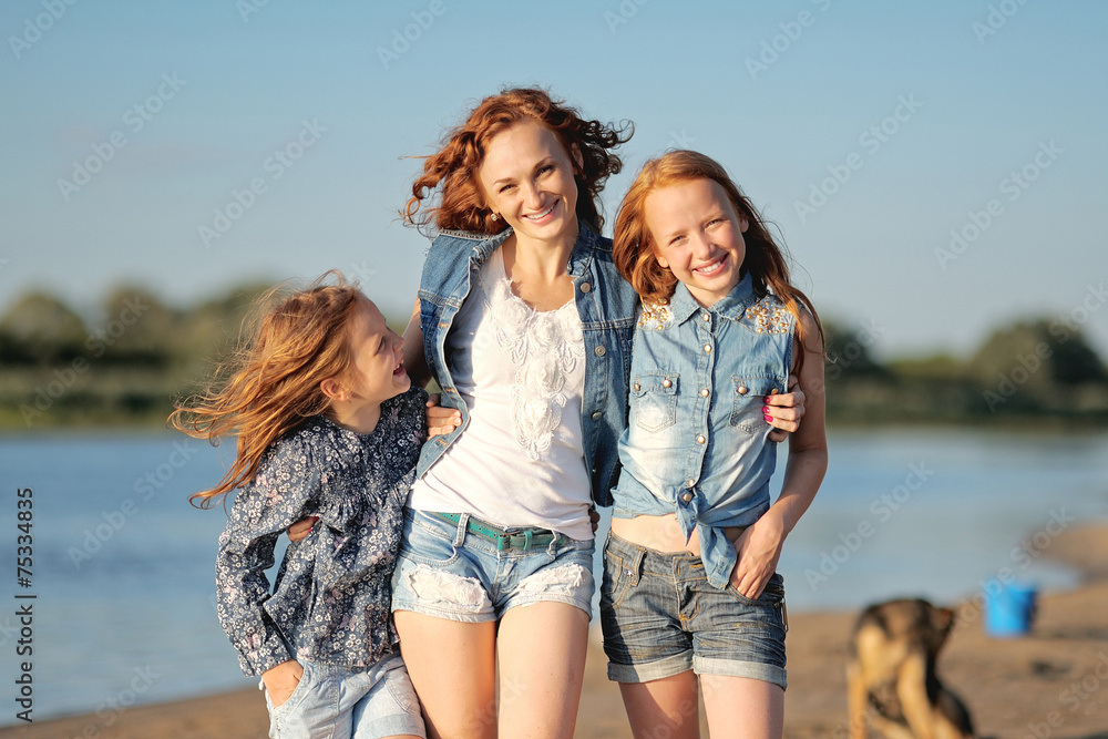 mother and her two daughters on the beach in summer mother and her two daughters on the beach in summer