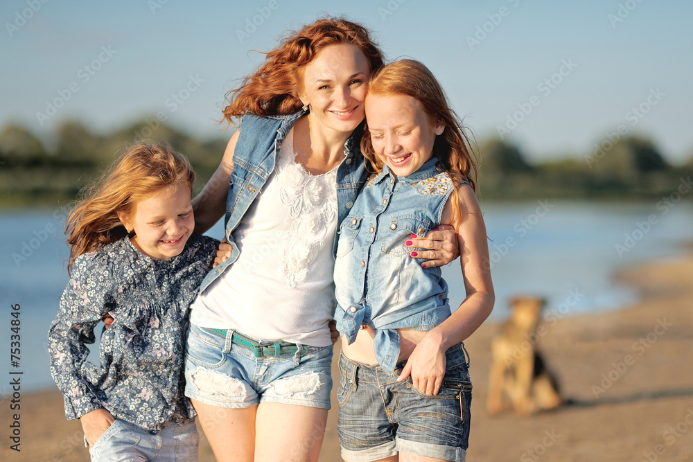 mother and her two daughters on the beach in summer mother and her two daughters on the beach in summer