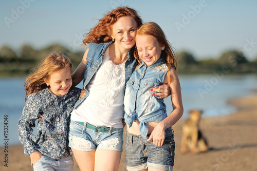 mother and her two daughters on the beach in summer