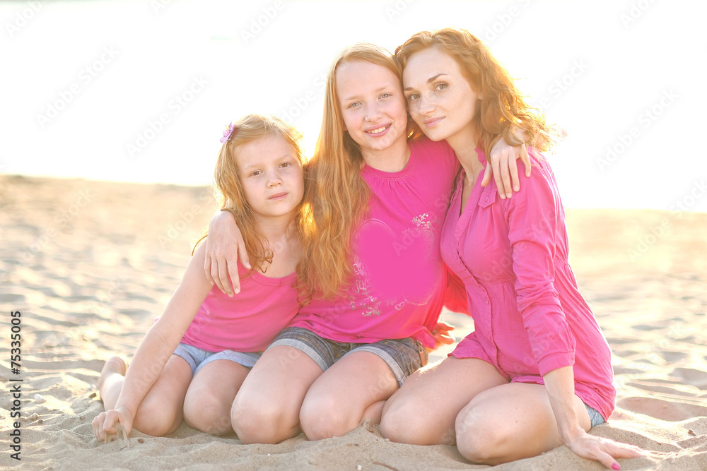 mother and her two daughters on the beach in summer mother and her two daughters on the beach in summer