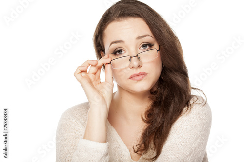 tired young woman looking through her glasses