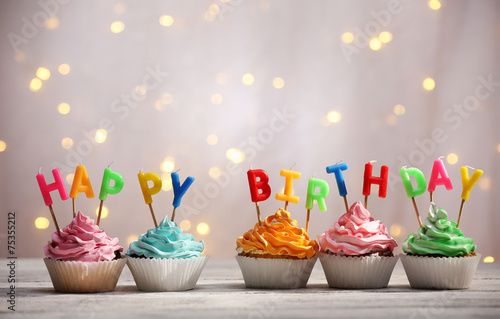 Photography Delicious birthday cupcakes on table on light background