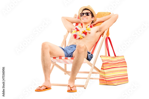 Fototapeta Young man enjoying seated in a sun lounger