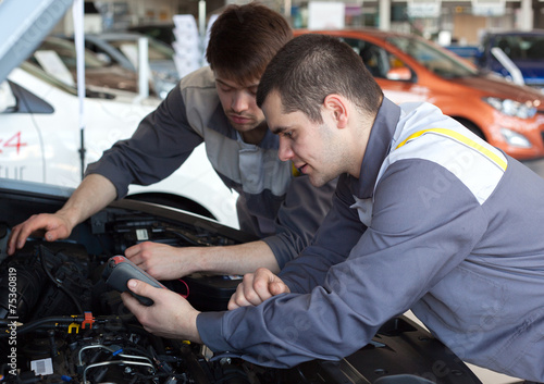 Mechanics at repair shop working on a car engine