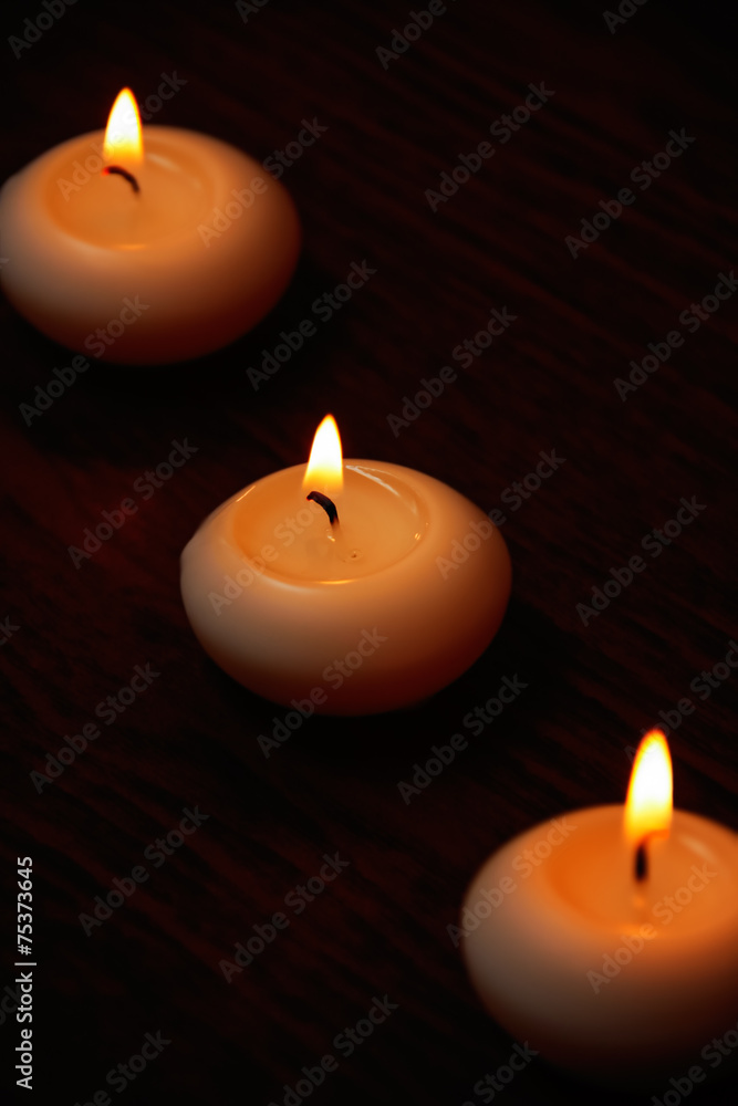 Three candles on a dark wooden table. Three candles on a dark wooden table.