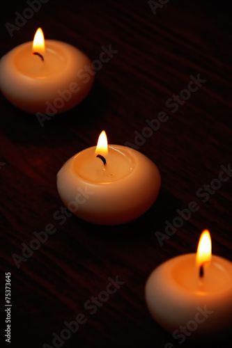 Three candles on a dark wooden table.