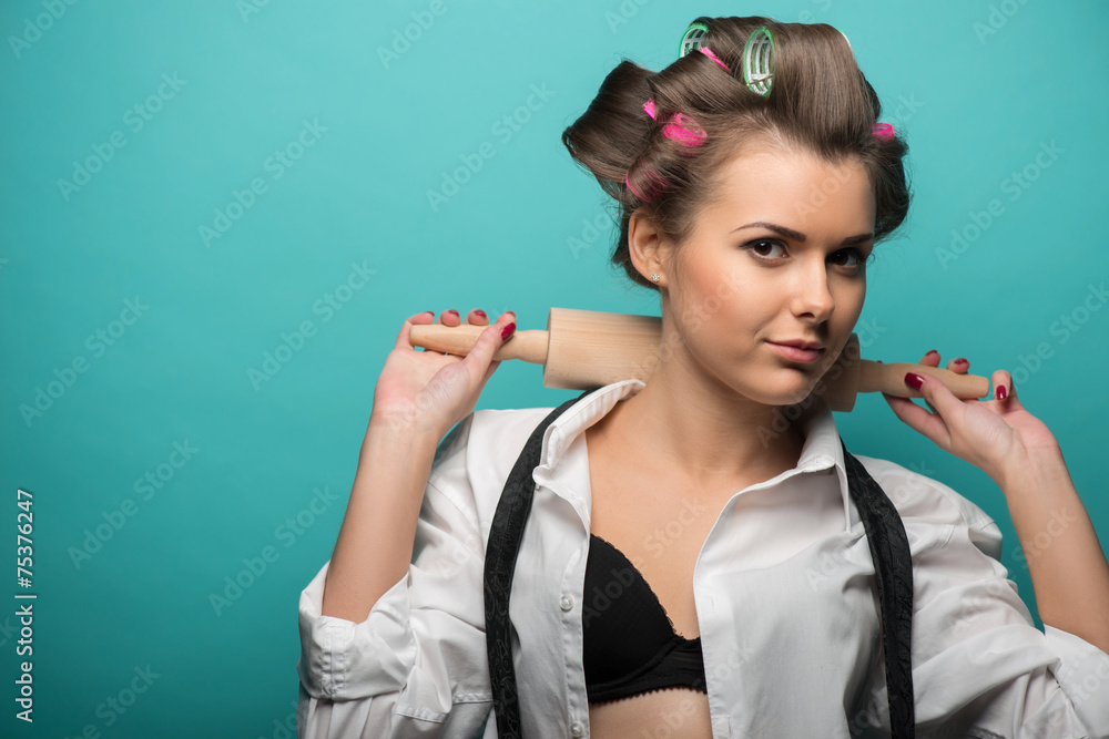Fototapeta premium Portrait of funny cute brunette woman in hair curlers wearing wh