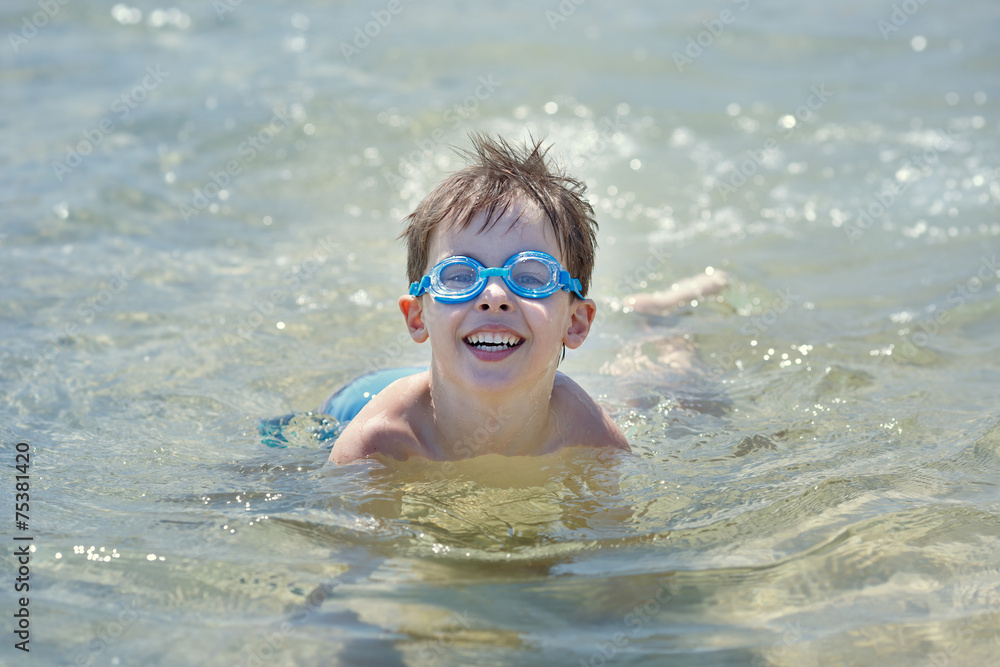 Cute little boy swimming in a shallow water