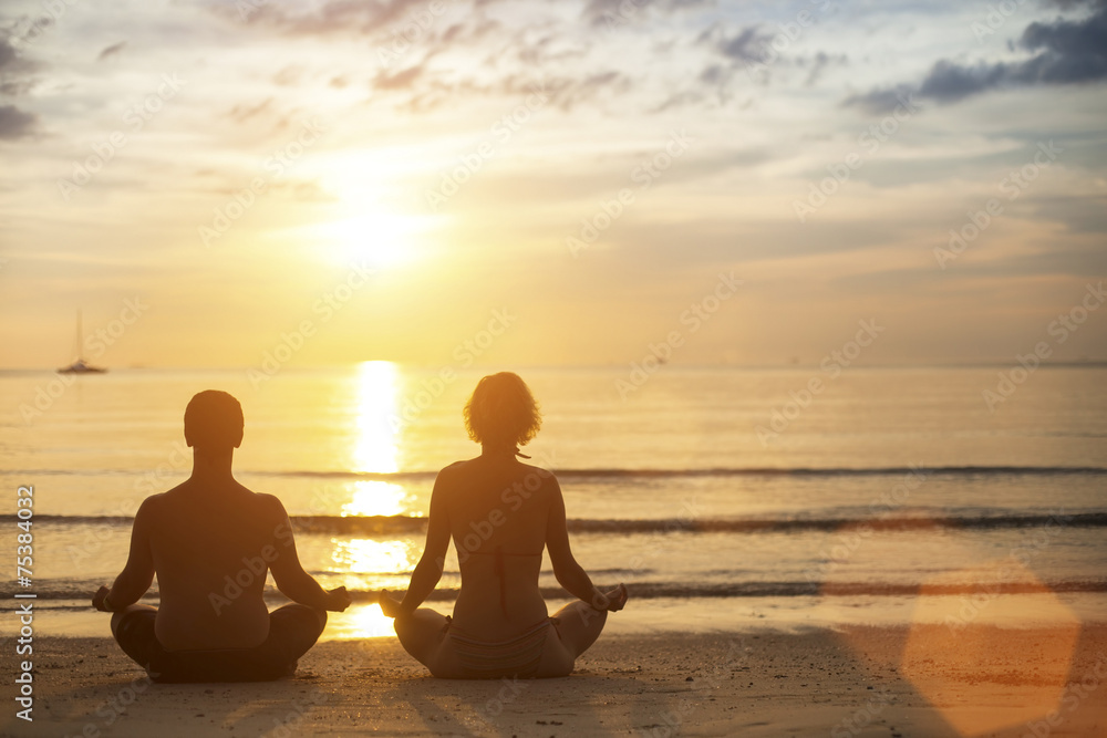 Young yoga couple meditating on the coast .