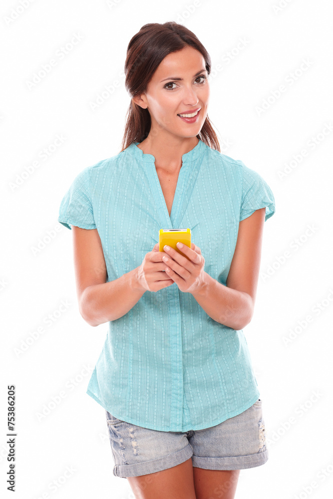 Cheerful latin girl using a yellow cellphone Cheerful latin girl using a yellow cellphone