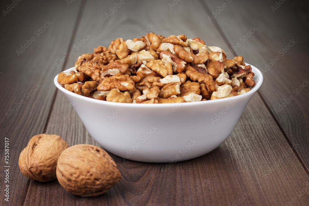 walnuts in the white bowl on wooden table walnuts in the white bowl on wooden table