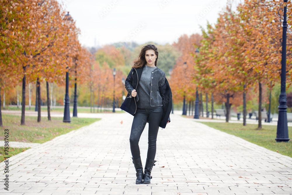 Happy woman in black coat walking autumn street