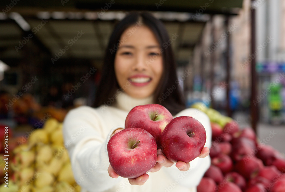 Young woman holding red apples in hand at market store Young woman holding red apples in hand at market store
