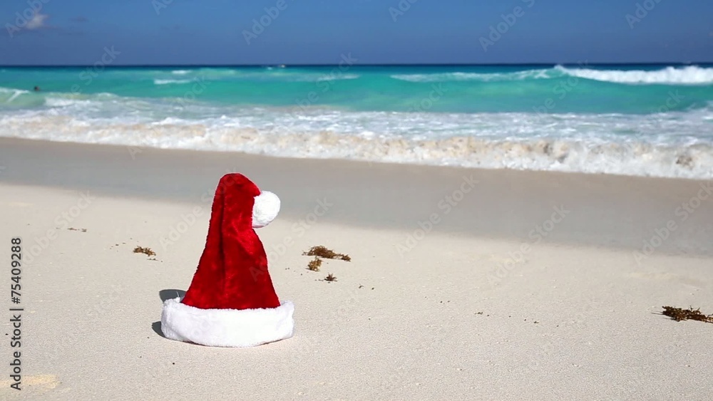 Santa Hat on white sandy beach with Caribbean sea background Santa Hat on white sandy beach with Caribbean sea background