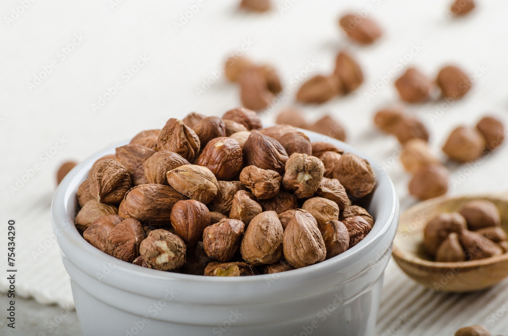 Hazelnuts in a bowl, spoon on the towel Hazelnuts in a bowl, spoon on the towel
