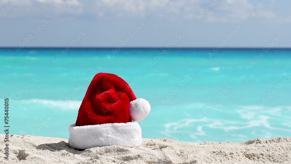 Santa Hat on white sandy beach with Caribbean sea background Santa Hat on white sandy beach with Caribbean sea background