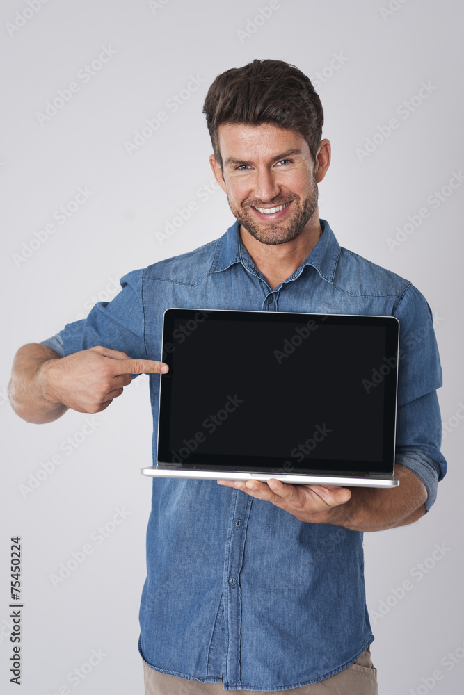 Smiling man pointing on screen of contemporary laptop Smiling man pointing on screen of contemporary laptop