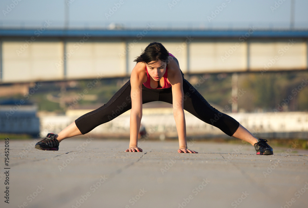 Young woman stretching leg muscles with hands on floor Young woman stretching leg muscles with hands on floor