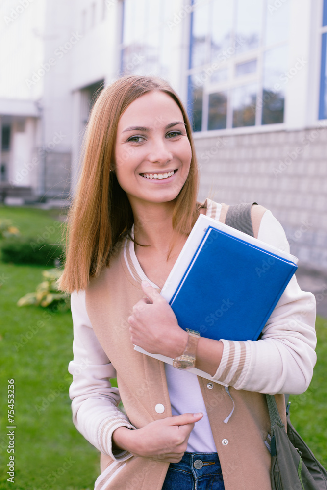 Student standing with book in her hands and laughing Student standing with book in her hands and laughing