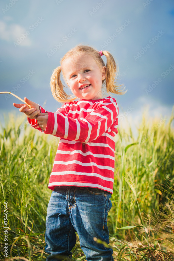 Little girl plays with between green grains Little girl plays with between green grains