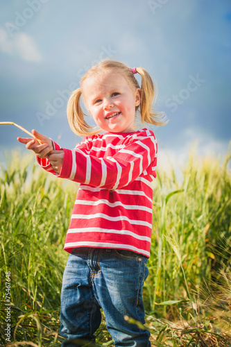 Little girl plays with between green grains