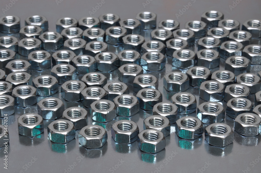 Shiny metal nuts on a metal surface Shiny metal nuts on a metal surface