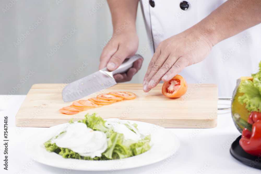 Chef's hands cutting Tomato