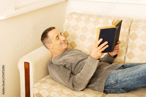Mature man reading a book at home