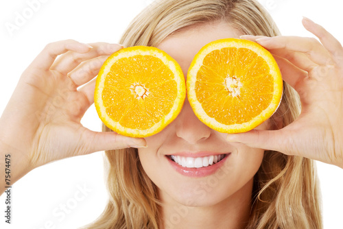 Young woman holding oranges on eyes